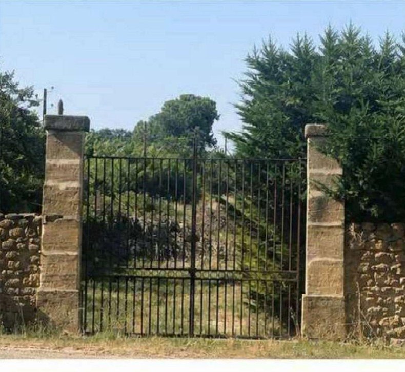 Portail ancien en fer forgé entre deux piliers de pierre
